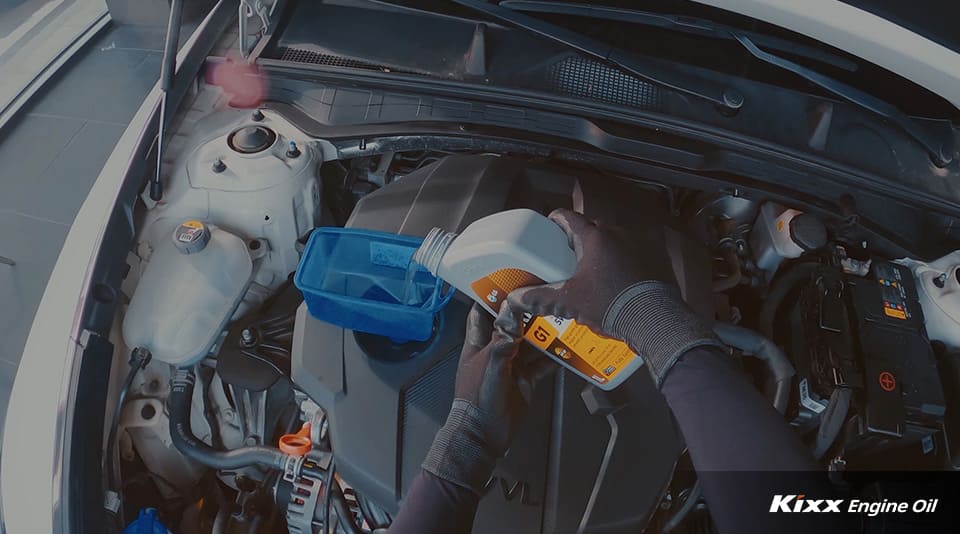 A mechanic pouring engine oil into the oil tank