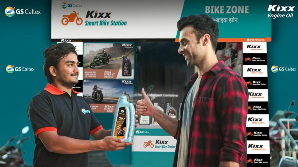 Kixx employee passing Kixx Engine oil to customer on the left, the customer on the right holds a thumbs up.  