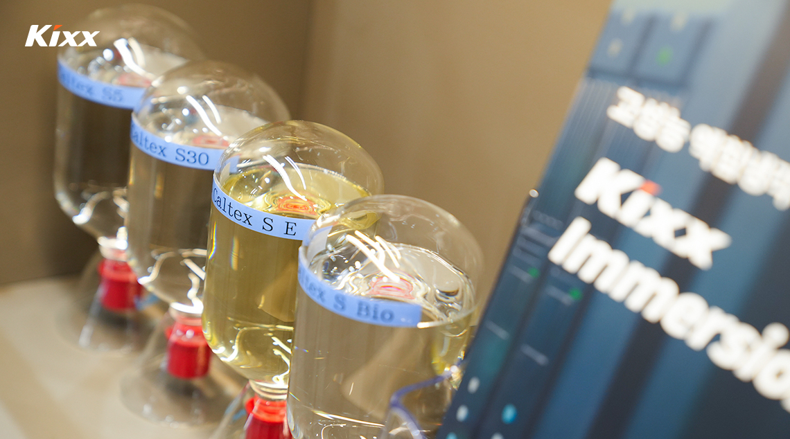 | Kixx Newsroom Glass containers filled with Kixx immersion cooling fluids displayed at exhibition booth.